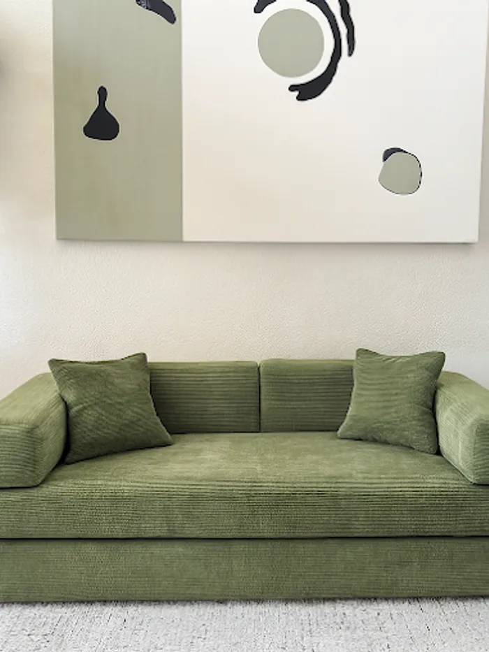 Living room with a green sofa and styled wall